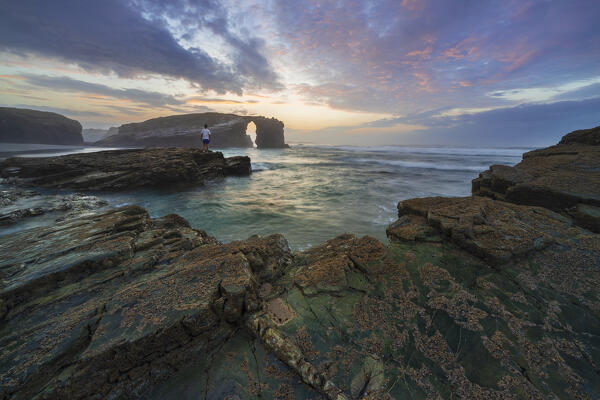 A man observes sunset at Playa de Las Catedrales at sunset, Ribadeo, Galicia, Spain, Iberian Peninsula, Western Europe