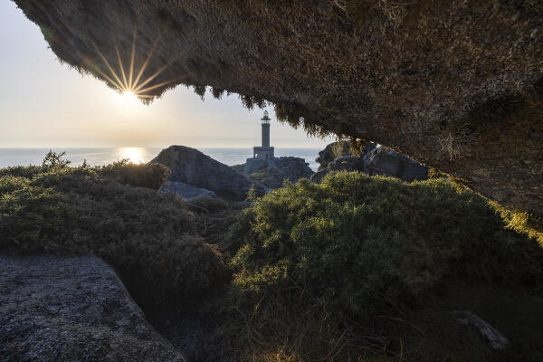 Punta Nariga lighthouse at sunset from a cave, Costa da Morte, Galicia, Spain, Iberian Peninsula, Western Europe