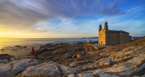 A woman observes Virxe da Barca Sanctuary at sunset during summer, Muxia, A Coruna, Galicia, Spain, Iberian Pensinsula, Western Europe