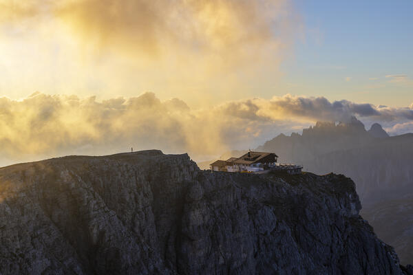 A person observes Lagazuoi refuge at sunrise during summer, Dolomiti di Badia and Zoldo, Belluno, Veneto, Italy, Southern Europe
