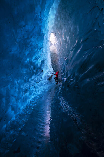 Man observes an ice cave of Breidamerkurjokull, Austurland, Iceland, Northern Europe