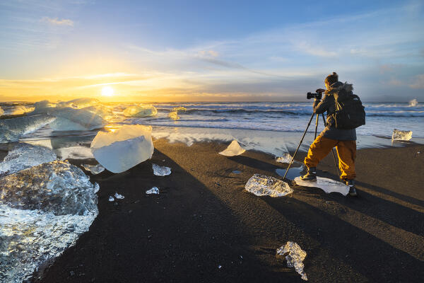 A photographer photographs Blocks of ice at sunrise at the Diamond Beach, Jökulsárlón, Diamond beach, Austurland, Iceland, Northern Europe (MR)