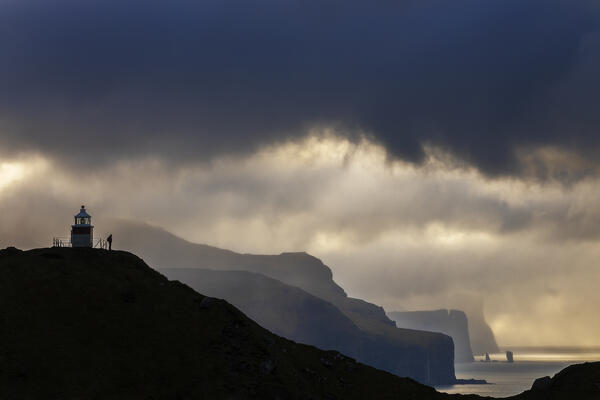 A trekker at Kallur lighthouse with a scenic view at sunset, Kalsoy, Faroe Islands, Denmark, Scandinavia