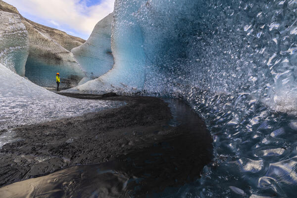 Man observes the entrance of an ice cave of Breidamerkurjokull, austurland, Iceland, Northern Europe
