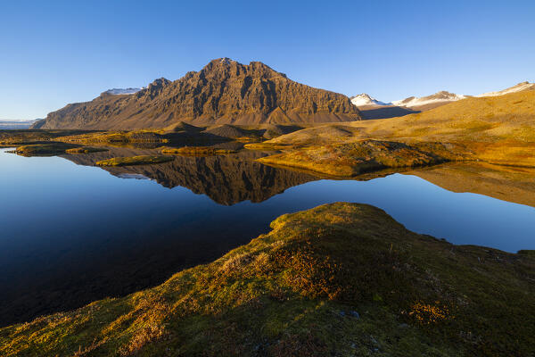 Fellsfjall mountain reflected along the road to Breidamerkurjokull at sunset, austurland, Iceland, Northern Europe
