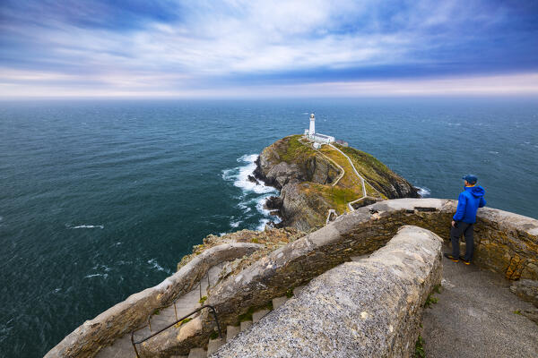 A tourist observes Irish sea an South Stack Lighthouse at sunset, Anglesey, Holy Island, Wales, Great Britain, United Kingdom