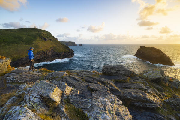 A tourist observes Atlantic Ocean from Boscastle Cliffs at sunset, Boscastle, Forraburry and Minster, Cornwall, United Kingdom, Northern Europe
