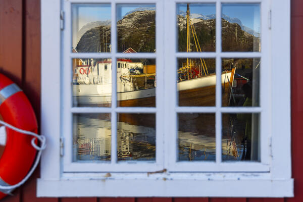 Reflections in a window of a Rorbu in Nusfjord, Flakstad, Flakstadoya, Nordland, Lofoten Islands, Norway, Northern Europe