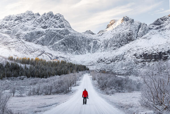 A photographer walks along the road to Nusfjord, Flakstad, Flakstadoya, Nordland, Lofoten Islands, Norway, Northern Europe (MR)