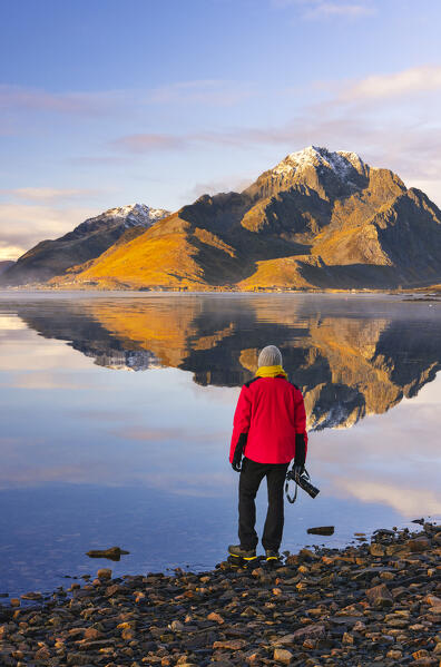 A photographer observes mountains and rorbuer in a Fjord during sunset, Leknes, Vestvagoy, Nordland, Lofoten Islands, Norway, Northern Europe (MR)