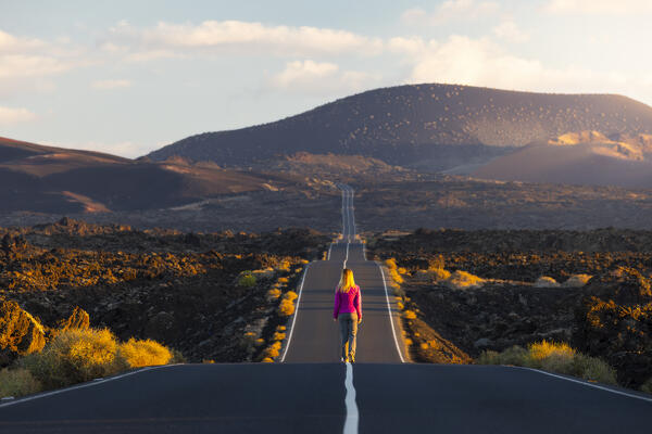 A tourist walks in the middle of Carretera infinita toward Timanfaya National Park at sunrise, Yaiza, Tinajo, Las Palmas, Lanzarote, Canary Islands, Macaronesia, Spain, Western Europe