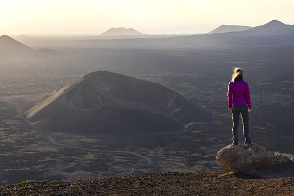 A woman observes Volcan El Cuervo at sunset from Montana Negra, Tinajo, Las Palmas, Lanzarote, Canary Islands, Macaronesia, Spain, Western Europe
