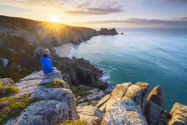 A tourist at Logan Rock and Pedn Vounder beach during sunrise, St Levan, Treen, Penzance, Cornwall, England, Great Britain, United Kingdom (MR)