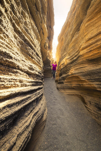 A tourist walks inside Las Grietas canyon, Las Palmas, LAnzarote, Canary Islands, Macaronesia, Spain, Western Europe