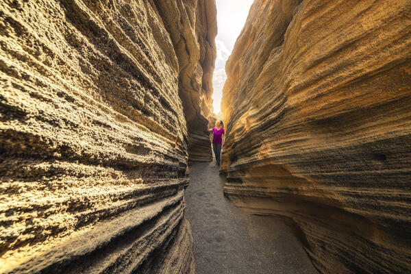 A tourist walks inside Las Grietas canyon, Las Palmas, Lanzarote, Canary Islands, Macaronesia, Spain, Western Europe