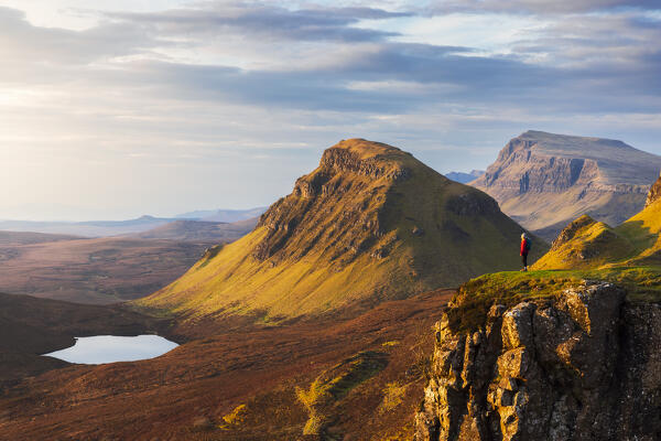 A tourist observes mountains from Quiraing viewpoint during sunrise, Isle of Skye, Inner Hebrides, Highlands, Scotland, United Kingdom (MR)