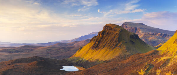 Panoramic view of mountains viewed from Quiraing during sunrise with moon, Isle of Skye, Inner Hebrides, Highlands, Scotland, United Kingdom