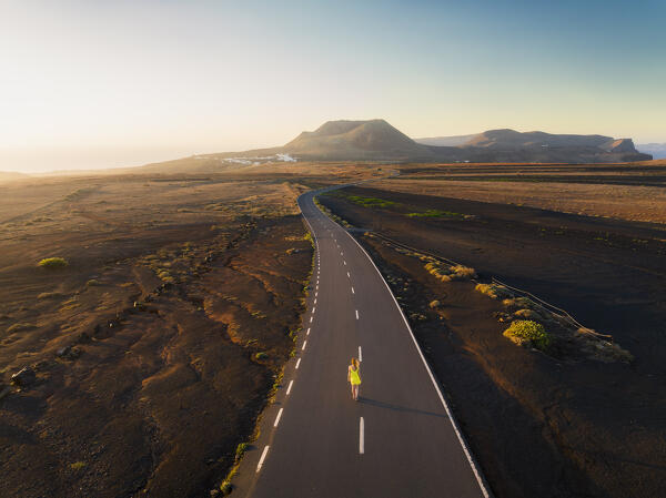 A tourist walks along the road that leads to the crater of Volcan de la Corona during sunrise, Mirador del Rio, Haria, Las Palmas, Lanzarote, Canary Islands, Macaronesia, Spain, Western Europe (MR)