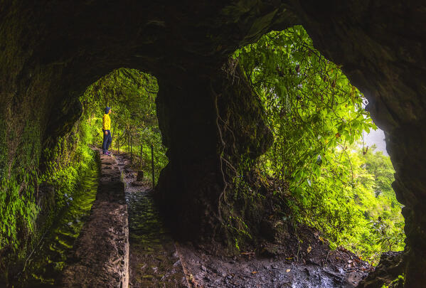 A tourist admires the beautiful nature of Levada do Caldeirao Verde from a cave along the route, Sao Vicente, Parque Florestal das Queimadas, Levada do Caldeirao Verde, Madeira region, Portugal, Western Europe
