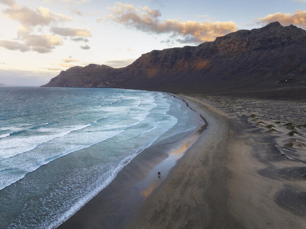 Aerial view of people walking around at Famara beach with its cliff during sunrise, Caleta de Famara, Las Palmas, Lanzarote, Canary Islands, Macaronesia, Spain, Western Europe