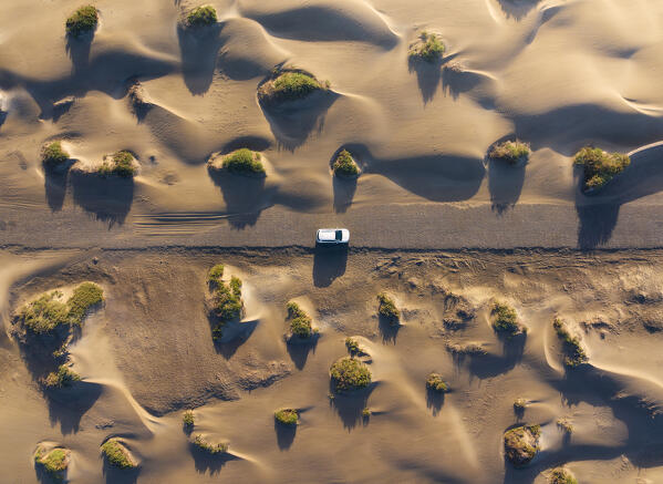 Aerial view of a car traveling through the sand dunes of Famara beach during sunrise, Caleta de Famara, Las Palmas, Lanzarote, Canary Islands, Macaronesia, Spain, Western Europe