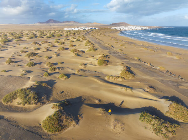Aerial view of a man over sand dunes of Famara beach during sunrise with Caleta de Famara in background, Caleta de Famara, Las Palmas, Lanzarote, Canary Islands, Macaronesia, Spain, Western Europe