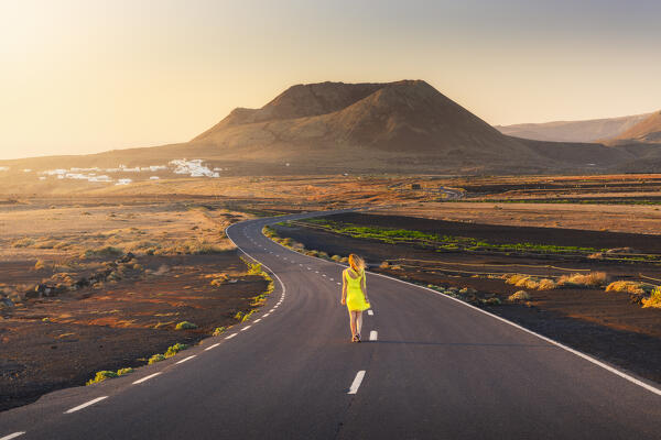 A tourist walks along the road that leads to the crater of Volcan de la Corona during sunrise, Mirador del Rio, Haria, Las Palmas, Lanzarote, Canary Islands, Macaronesia, Spain, Western Europe