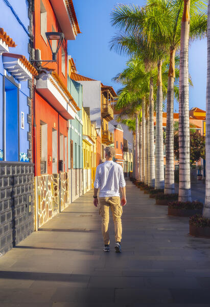A man walks in a road of Puerto de la Cruz surrounded by colorful houses, Puerto de La Cruz, Tenerife, Canary Islands, Macaronesia, Spain, Western Europe 