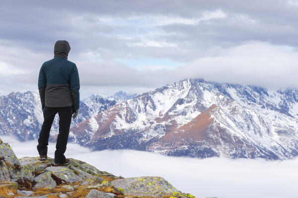 A man at Paradise Pass over Tonale Pass observes mountains and clouds in front of him, Ponte di Legno, Brescia, Lombardia, Italy, Southern Europe