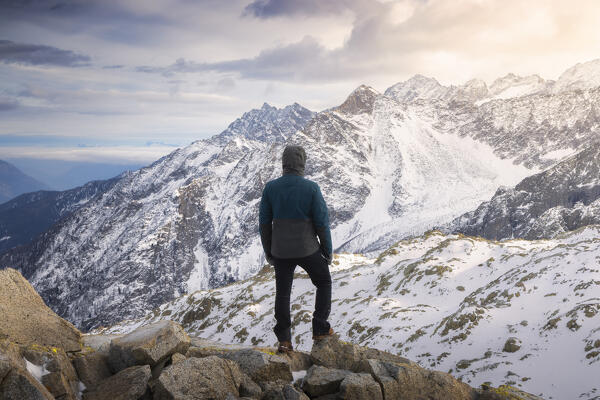 A man at Paradise Pass over Tonale Pass observes Cima Presanella and Cima Palù in front of him, Trento, Trentino Alto Adige, Italy, Southern Europe
