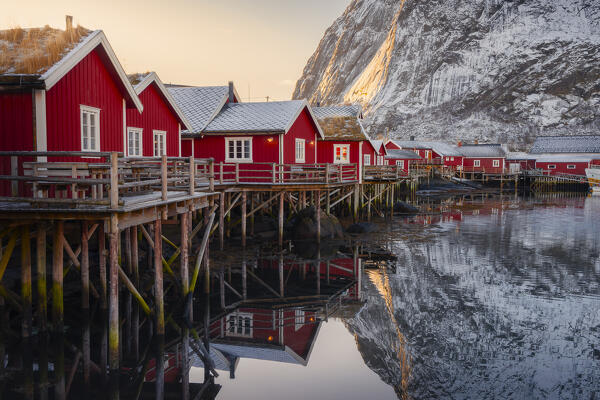 Reine small harbour with mountains in the backgroung during winter sunset with reflections, Moskenes, Moskenesoya, Nordland, Lofoten, Norway, Northern Europe