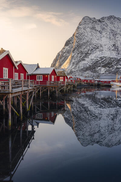 Reine small harbour with mountains in the backgroung during winter sunset with reflections, Moskenes, Moskenesoya, Nordland, Lofoten, Norway, Northern Europe