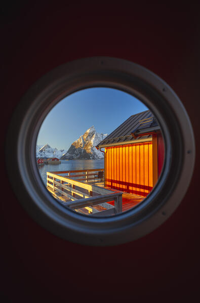 The view of the bay through a porthole of a rorbu door in Hamnoy with the, Hamnoy, Moskenes, Moskenesoya, Nordland, Lofoten, Norway, Northern Europe