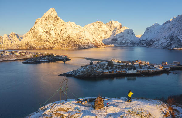Aerial view of a photographer at Olenilsoya kystfort while watching Sakrisoy and Hamnoy bay at sunrise with Olstinden in the background, Hamnoy, Moskenes, Moskenesoya, Nordland, Lofoten, Norway, Northern Europe