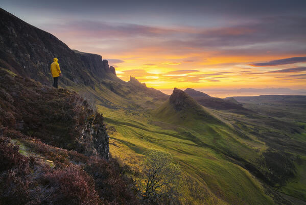 Tourist observes mountains and sunrise from Quiraing viewpoint during sunrise, Isle of Skye, Inner Hebrides, Highlands, Scotland, United Kingdom