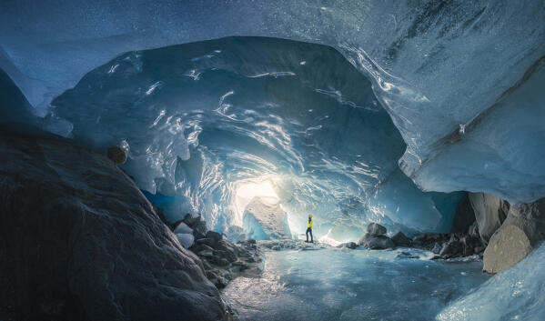 Panoramic view of a trekker inside an ice cave of Morteratsch glacier during winter, Bernina Valley, Grigioni, Switzerland, Western Europe
