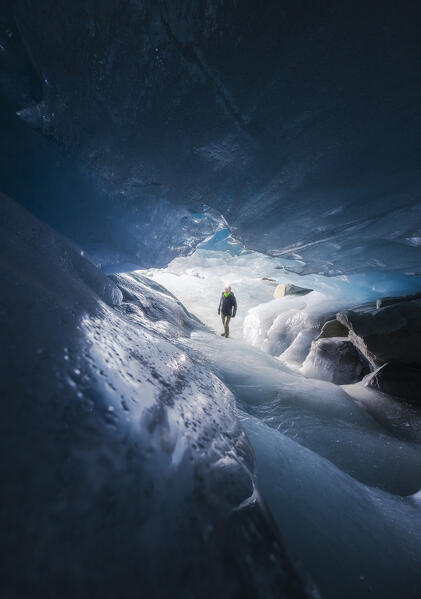 A trekker inside an ice cave of Morteratsch glacier during winter, Bernina Valley, Grigioni, Switzerland, Western Europe