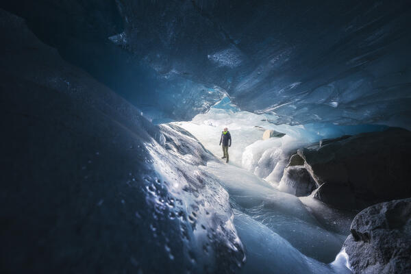 A trekker inside an ice cave of Morteratsch glacier during winter, Bernina Valley, Grigioni, Switzerland, Western Europe