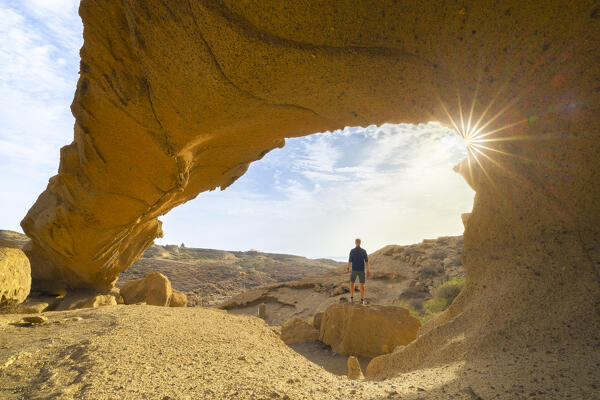 A tourist observes Arco de Tajao at sunrise, San Miguel de Tajao, Arico, Santa Cruz de Tenerife, Tenerife, Canary Islands, Macaronesia, Spain, Western Europe