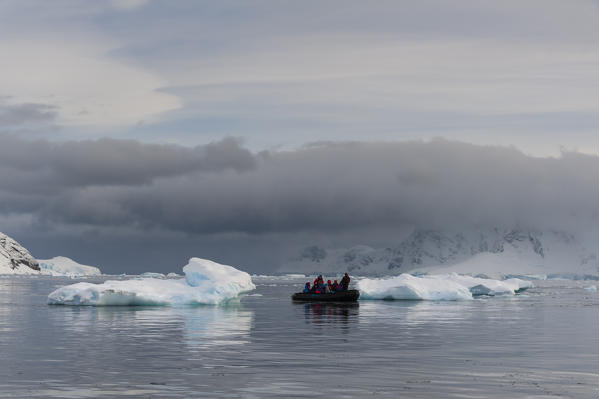 Tourist exploring Skontorp cove in inflatable boat, Paradise Bay, Antarctica.