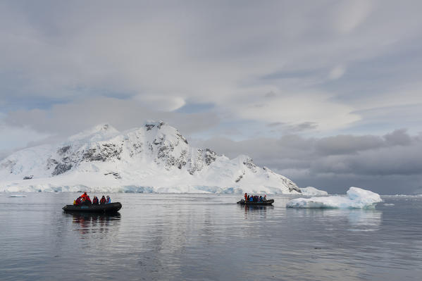 Tourist exploring Skontorp cove in inflatable boat, Paradise Bay, Antarctica.