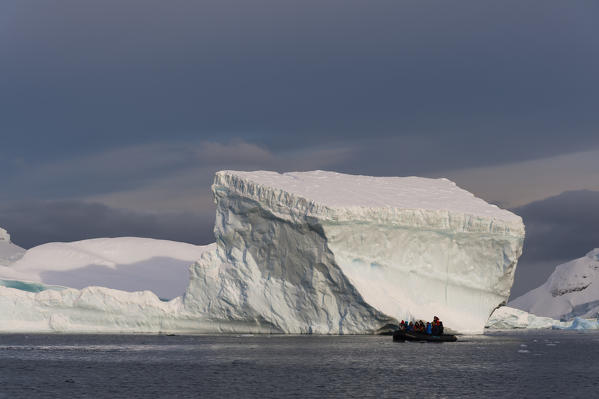 Tourist exploring Skontorp cove in inflatable boat, Paradise Bay, Antarctica.