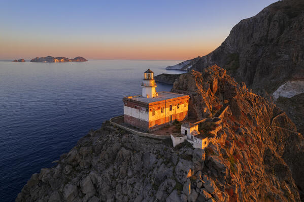 Aerial view of the lighthouse of Punta della Guardia peak with the mediterranean island of Palmarola lit from the sun at sunrise, Ponza island, Archipelago Pontino, Latina province, Latium, Italy