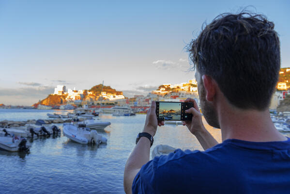 Tourist taking picture with his smartphone at the colourful mediterranean village of Ponza, Ponza island, Archipelago Pontino, Latina province, Latium, Italy (MR)