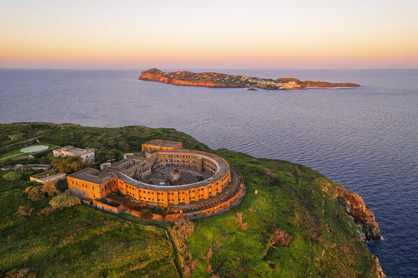 The panopticon prison on top of Santo Stefano Island lit at sunrise with Ventotene island in the background, Santo stefano and Ventotene Islands, Pontine Islands archipelago, Tyrrhenian Sea, Latina province, Latium, Italy, Europe