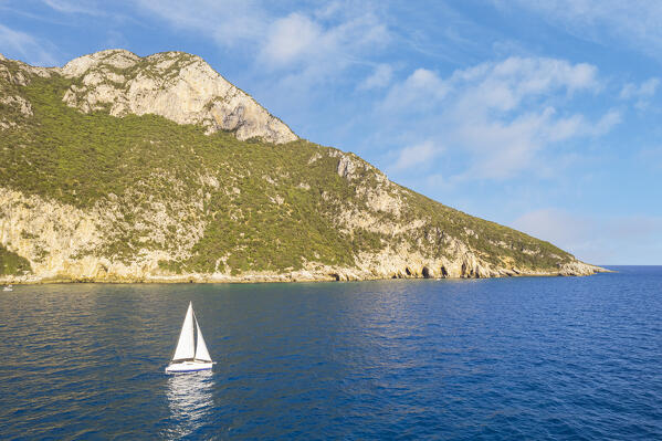 White sailing boat sails the blue water off the coast of Circeo with Circe's with caves in the background, Circeo National Park, Tyrrhenian sea, Mediterranean sea, Latina province, Latium, Central Italy, Italy, Southern Europe, Europe