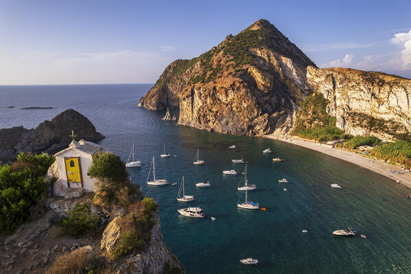 Drone shot of the white chapel of the Saint Silverio on top of a cliff in front of the bay of Palmarola with boats moored, Ponza municipality, Pontine archipelago, Latina province, Latium region, Tyrrhenian Sea, Italy, Europe