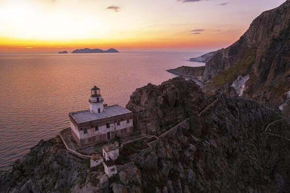 Aerial view of Punta della Guardia lighthouse on top of a basaltic cliff with Palmarola island in the background at sunset, Pinza island, Tyrrhenian sea, Pontine archipelago, Latina province, Latium, Italy, Europe
