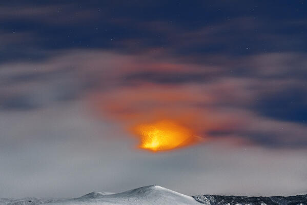 Night view of lava fountains seen behind the clouds from the eruption of the South-East crater of volcano Etna, winter view, Piano Vetore, Regalna, Catania province, UNESCO World heritage Site, Sicily, Mediterranean Sea, Southern Italy, Italy, Southern Europe, Europe