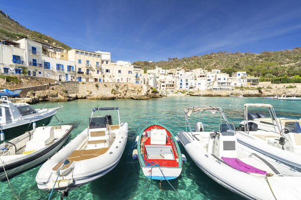 Boats frame the white village and turquoise sea of Levanzo island, Favignana municipality, Trapani, Aegadian islands, Mediterranean Sea, Sicily, Italy